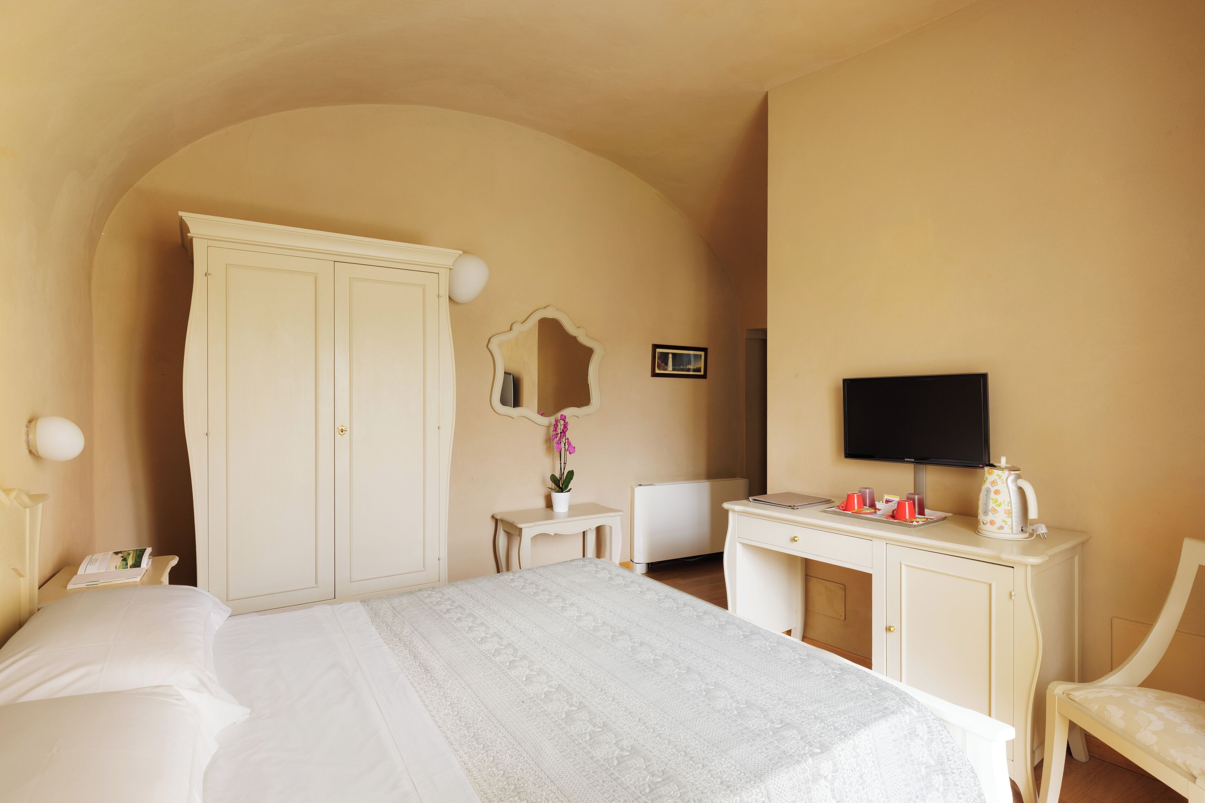 A hotel room with a bed, a desk, a chair, a television, and a wardrobe.