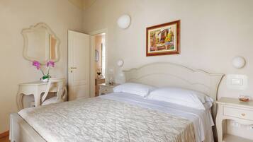 A bedroom with a bed, a bedside table, a dresser, a mirror, and a wall-mounted picture.