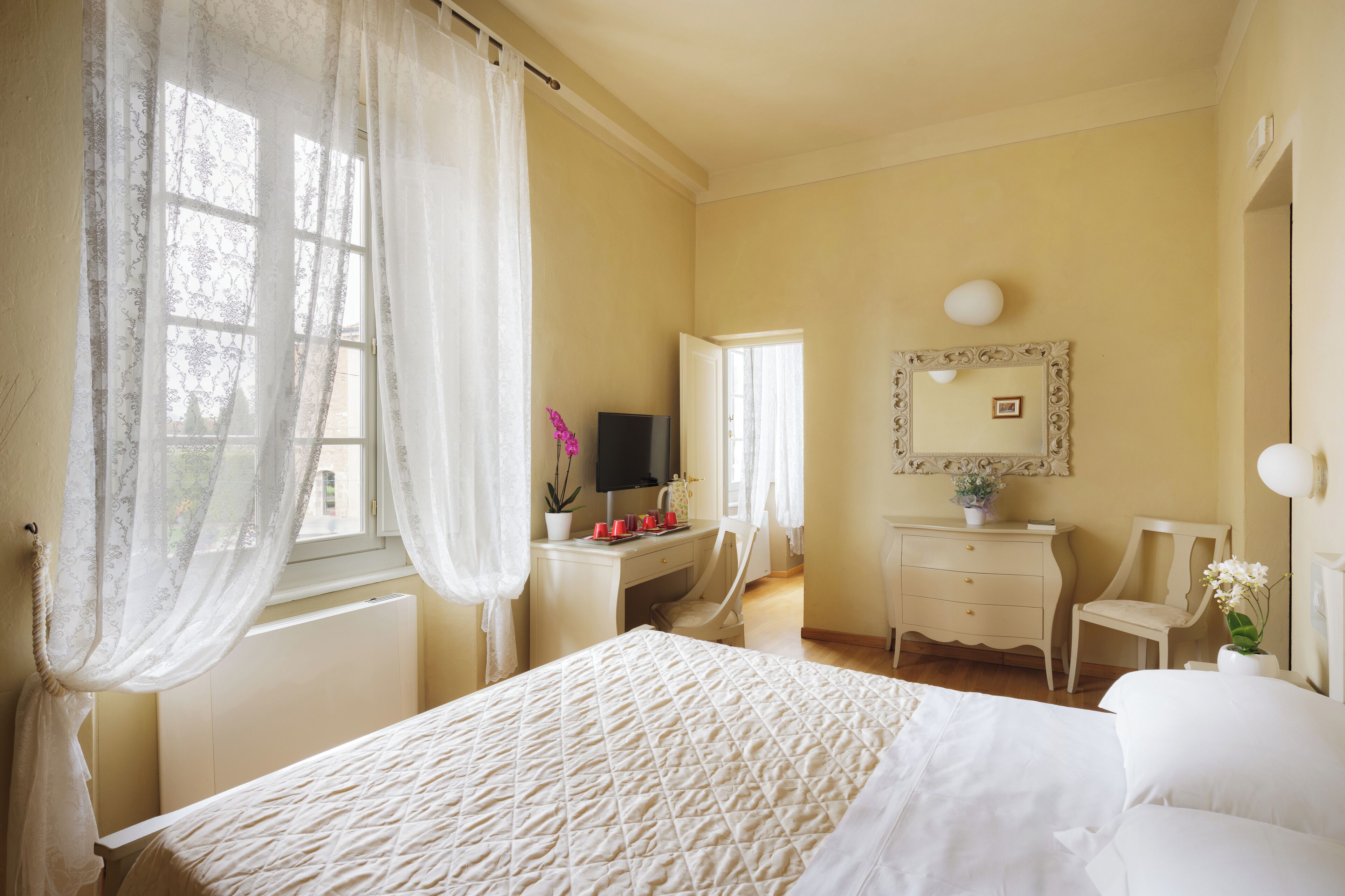 A bedroom with a bed, a desk, a chair, a dresser, and a mirror.