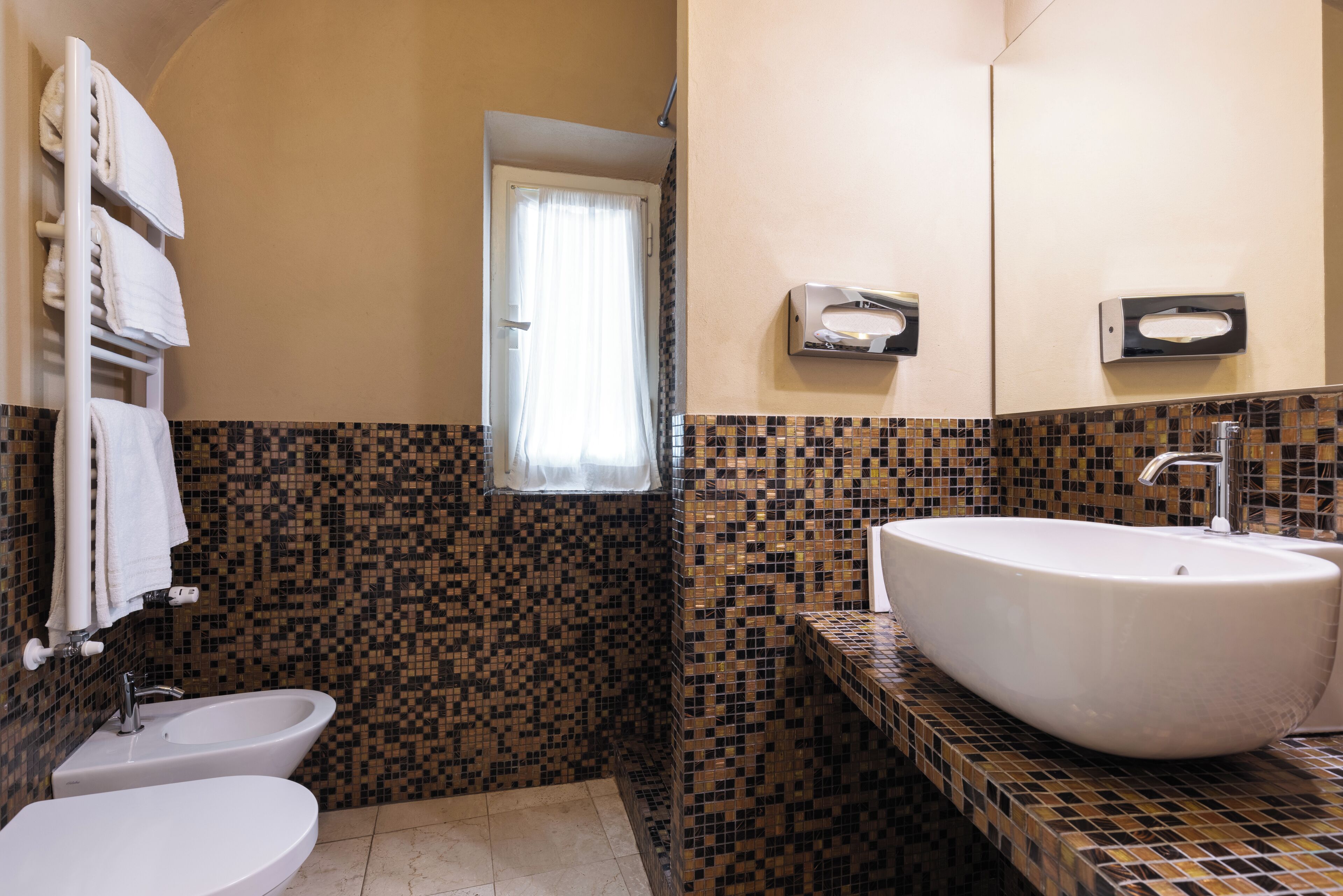 Un baño con lavamanos blanco, un bidé y un espejo.