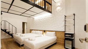 A hotel room with two beds, a built-in heater, a wooden floor, and a staircase. -  Green House Hotel (Barcelona)