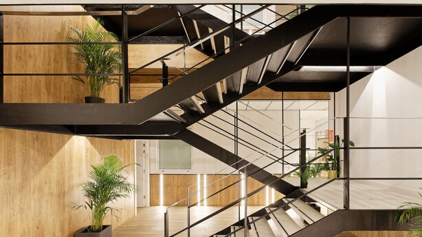 A modern staircase with a black metal frame and wooden accents, leading to an upper level with a view of the interior space. -  Green House Hotel (Barcelona)