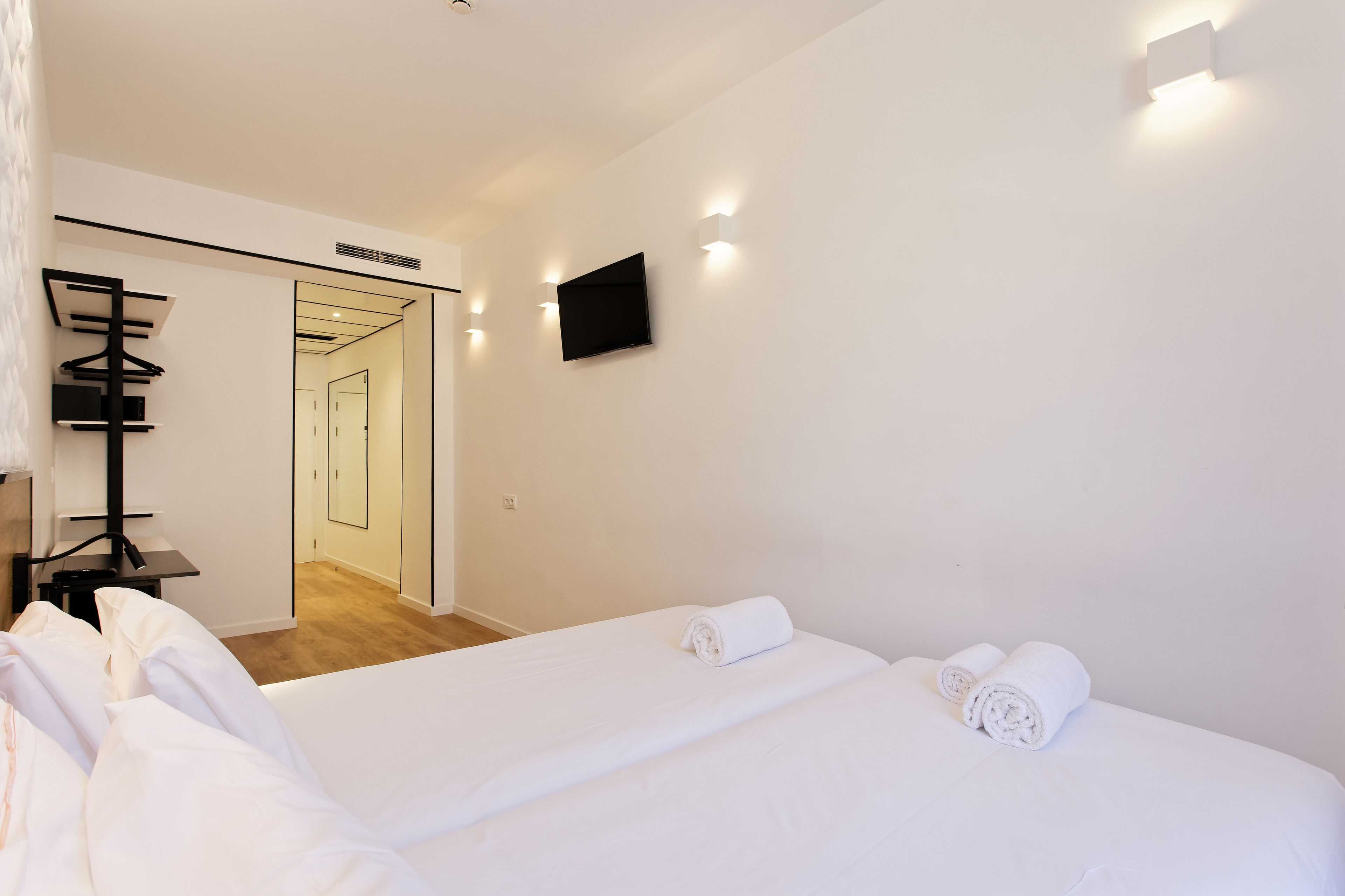 Ein Hotelzimmer mit einem Bett, einem an der Wand befestigten Fernseher und einem Spiegel an der Tür.