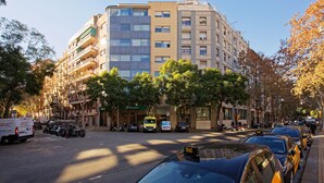 A multi-story building with balconies, parked vehicles, and trees lining the street. -  Green House Hotel (Barcelona)