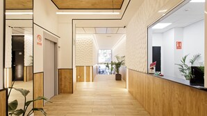 A modern reception area with a wooden floor, a reception desk, and potted plants. -  Green House Hotel (Barcelona)
