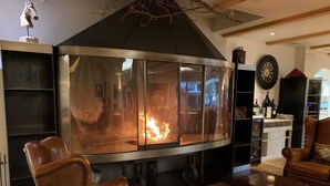 Una zona de estar acogedora con sillones de cuero, una chimenea de vidrio y una estantería para vinos.