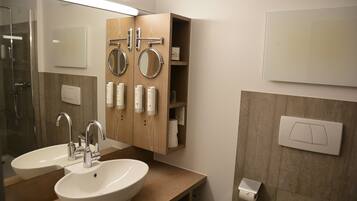 A bathroom with two sinks, a mirror, and a shower.