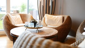 Una habitación con muebles de mimbre, una mesa redonda de madera con una bandeja y vistas al exterior.