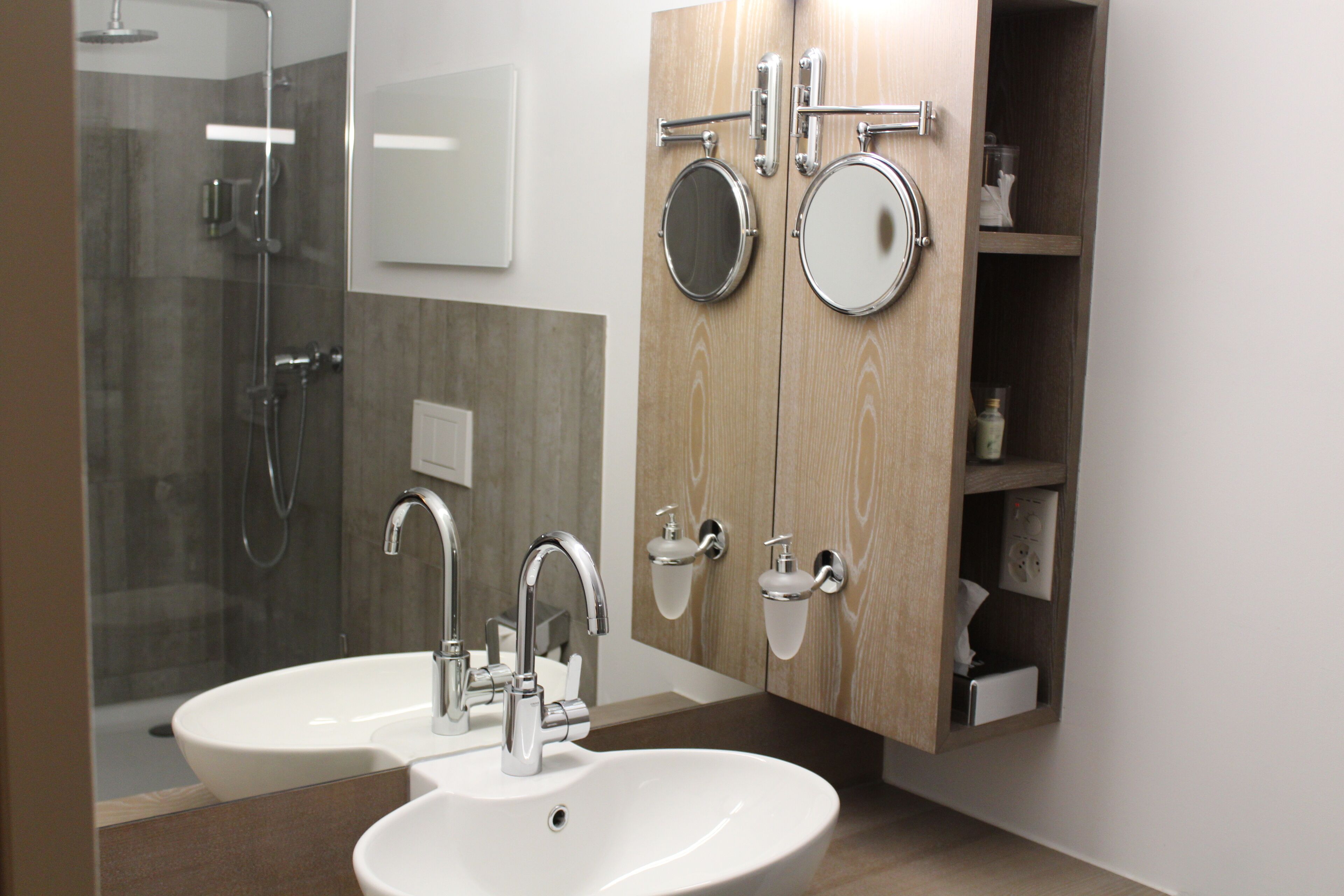 Un baño moderno con dos lavamanos, ducha y espejo.