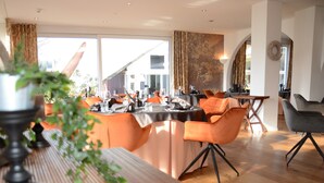 Un comedor con una mesa larga, sillas anaranjadas y un diseño interior moderno.