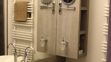 A bathroom with a large sink, two mirrors, a towel rack, and a cabinet with shelves.