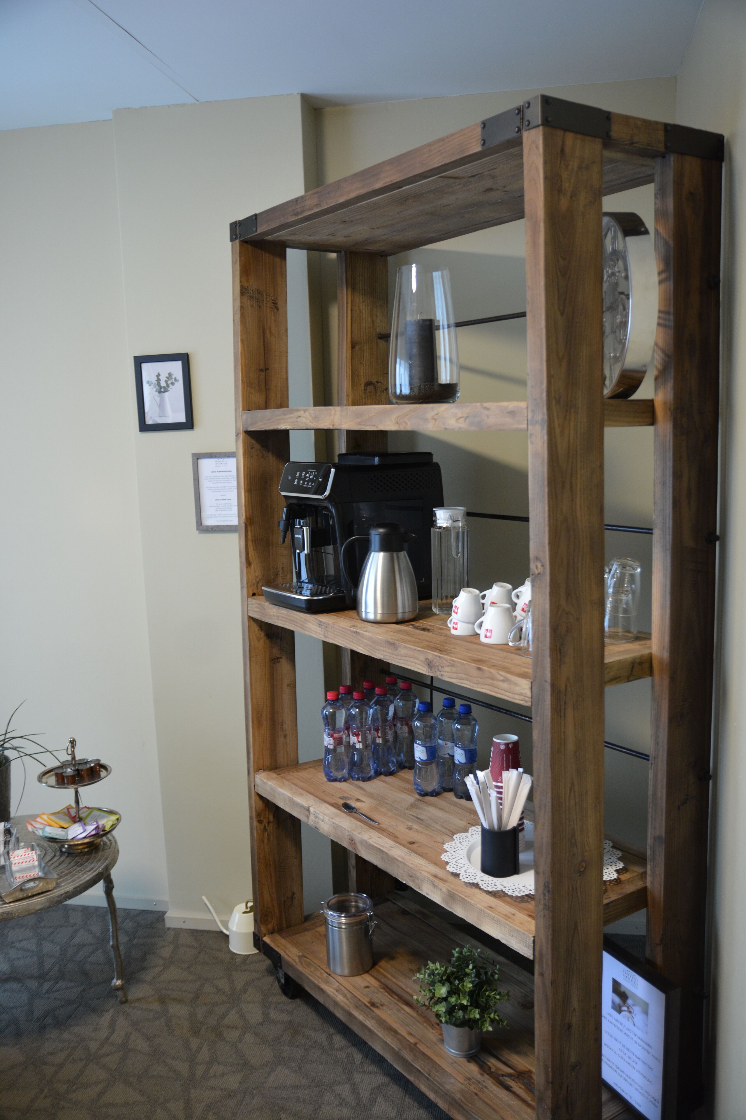 Une étagère en bois contenant divers articles de cuisine, notamment une machine à café, des tasses et des bouteilles.