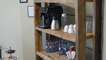 A wooden shelving unit with various kitchen items including a coffee maker, cups, and bottles.