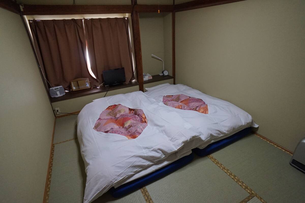 A room with a bed, a desk with a lamp, and a window with curtains.