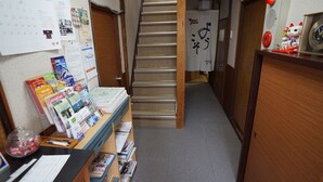 A hallway with a staircase, a desk with books and papers, and a calendar on the wall. - Ryokan Katsutaro (Tokyo)