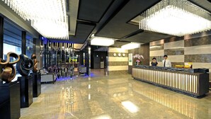 A modern lobby with a reflective floor, a reception desk, and a chandelier. - International Citizen Hotel (Kaohsiung)