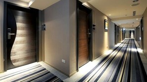 A hotel hallway with striped carpet, doors, and recessed lighting. - International Citizen Hotel (Kaohsiung)