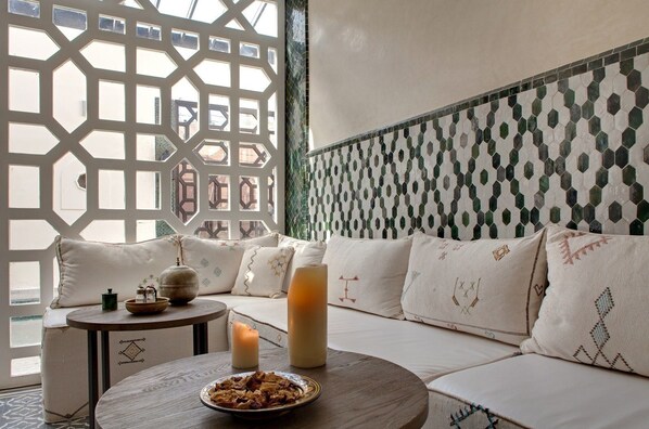 A cozy seating area with a sofa, cushions, a small table with a candle, and a decorative bowl. - Palais de l'Ô (Marrakech)