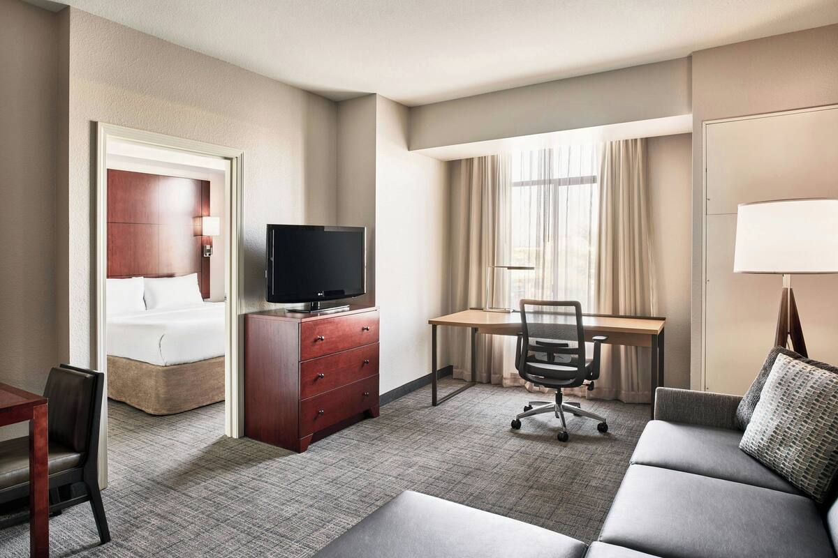 A hotel room with a bed, a desk, a television, a sofa, and a chair.