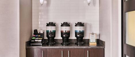 A coffee station with three espresso machines, a coffee grinder, and a menu sign.