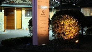 A tall sign with the name "Bentleys" and amenities listed, in front of a building with a modern roof and a well-lit entrance.