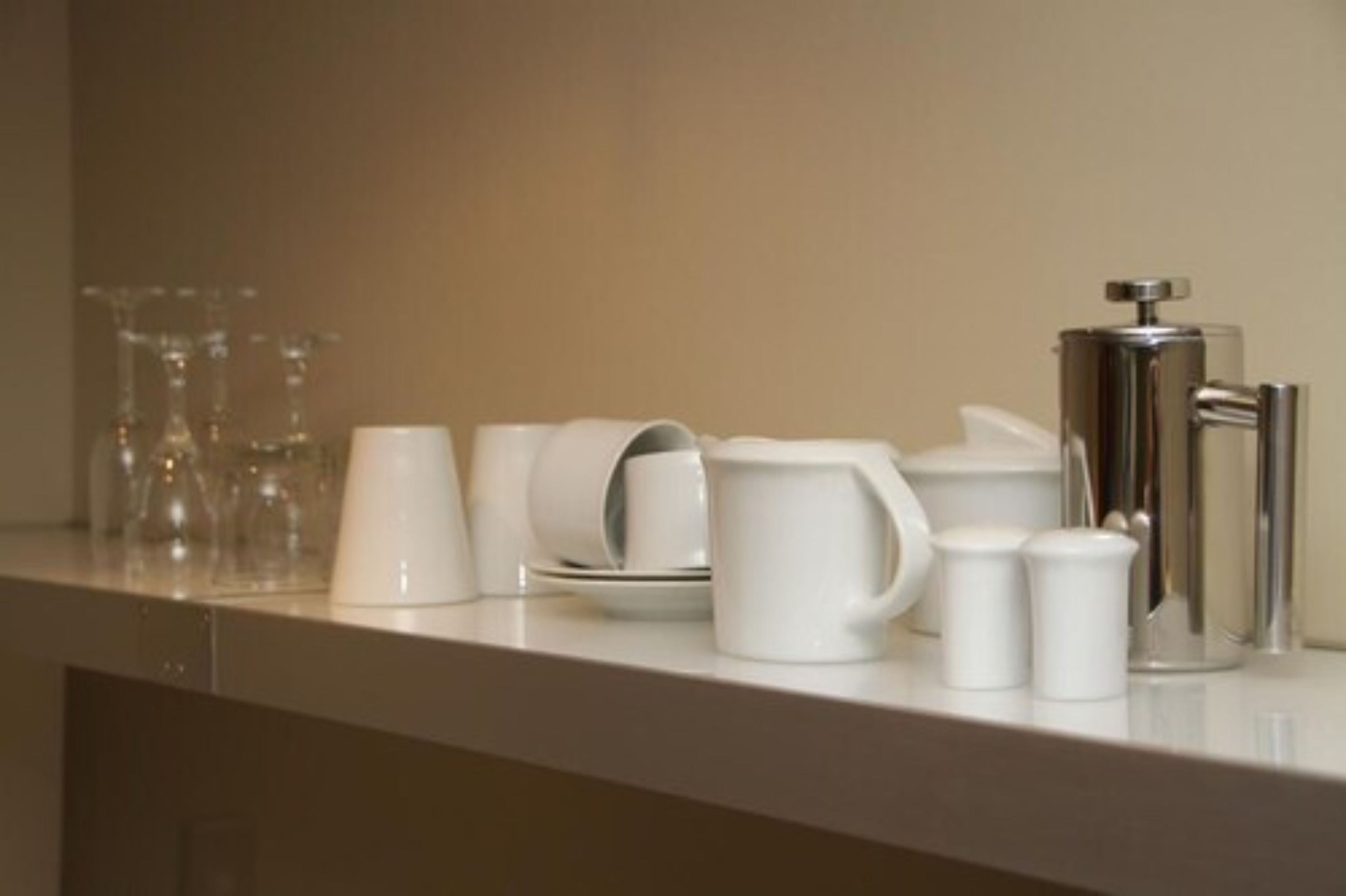 Un plan de travail sur lequel sont disposés divers objets en céramique blanche, notamment des tasses, une cafetière, ainsi que des salières et des poivrières.
