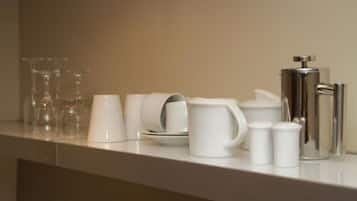 Un plan de travail sur lequel sont disposés divers objets en céramique blanche, notamment des tasses, une cafetière, ainsi que des salières et des poivrières.
