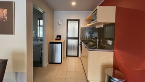 A compact kitchen with a refrigerator, microwave, sink, and a small trash bin.