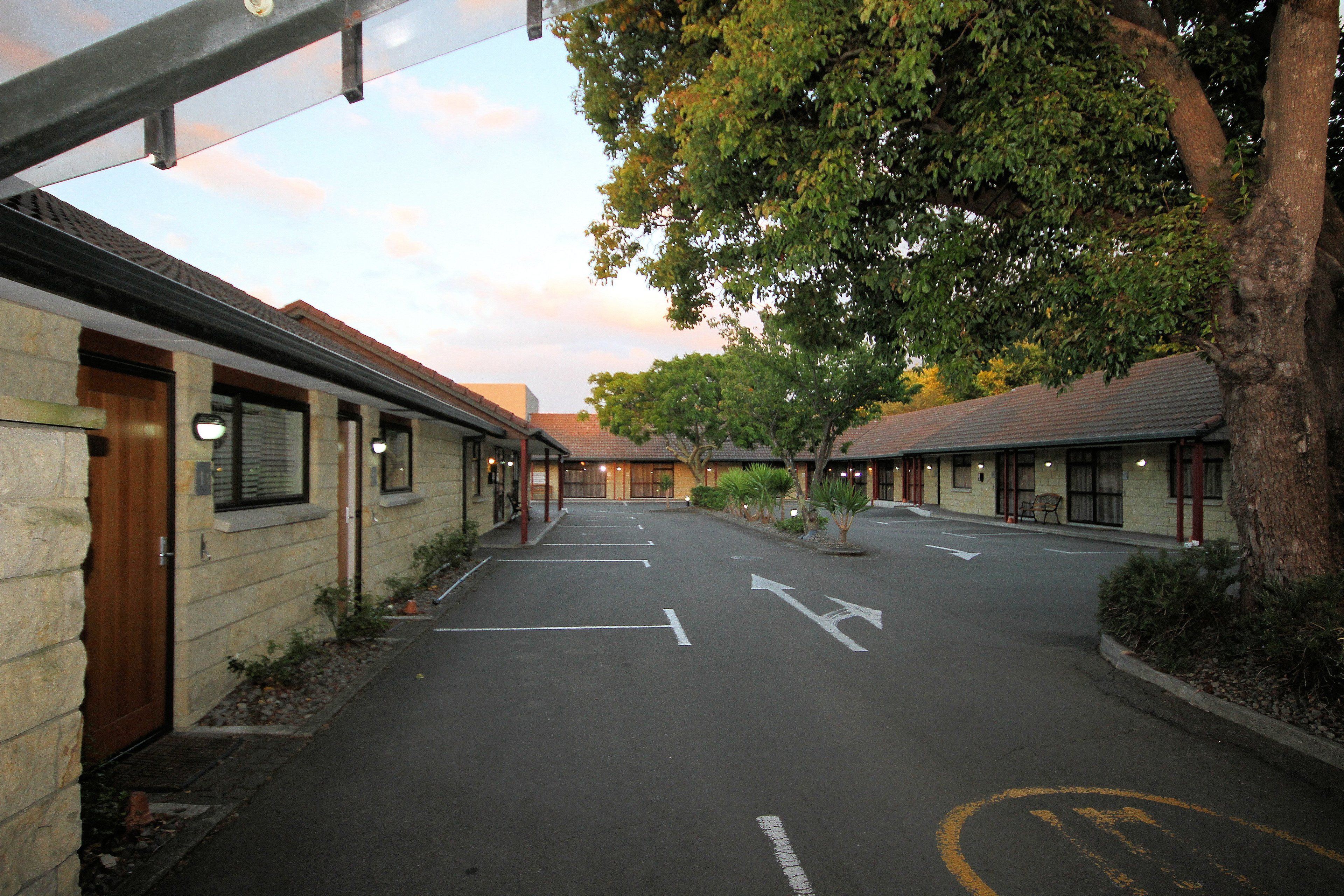 A street view of a row of buildings with a clear road marked with directional arrows.