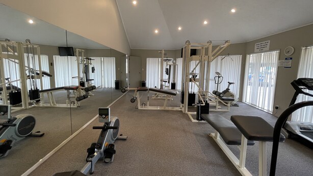 A gym with various exercise equipment, large windows, and a mirror.