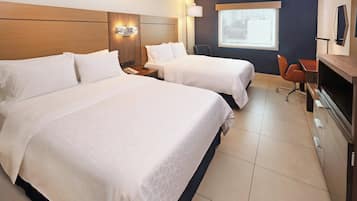 Habitación de hotel con dos camas, un escritorio, una silla, un televisor y ventana con vistas.