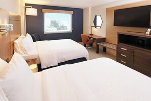 A hotel room with two beds, a desk, a chair, a TV, and a window with a city view.