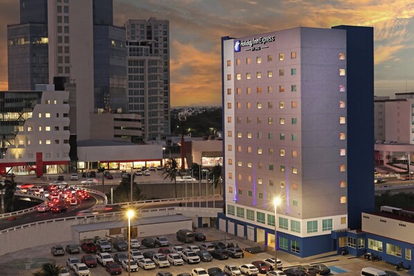 A Holiday Inn Express hotel with a parking lot and surrounding urban buildings.