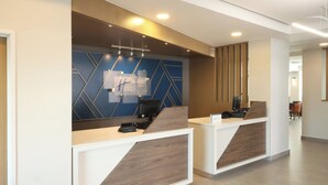 A modern reception desk with a geometric wall design and a computer monitor. - Holiday Inn Express Veracruz Boca Del Rio by IHG (Boca del Río)