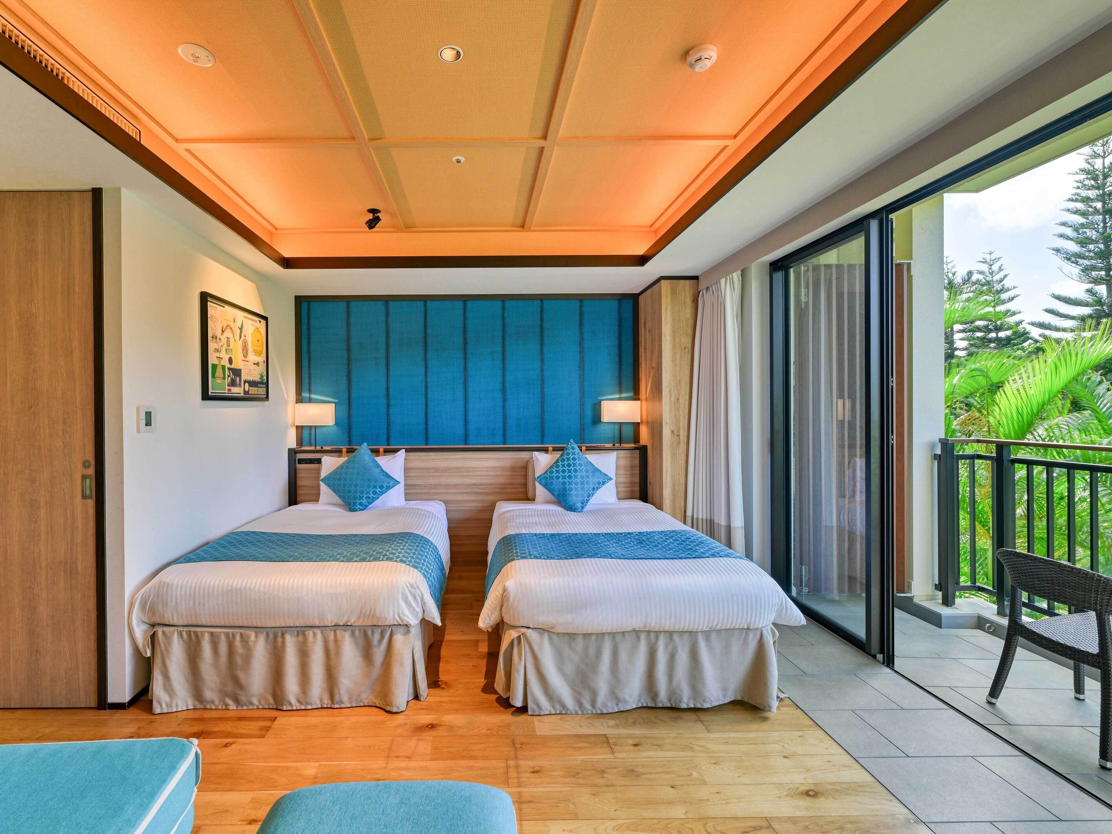 Habitación de hotel con dos camas, un ventanal grande y un balcón.