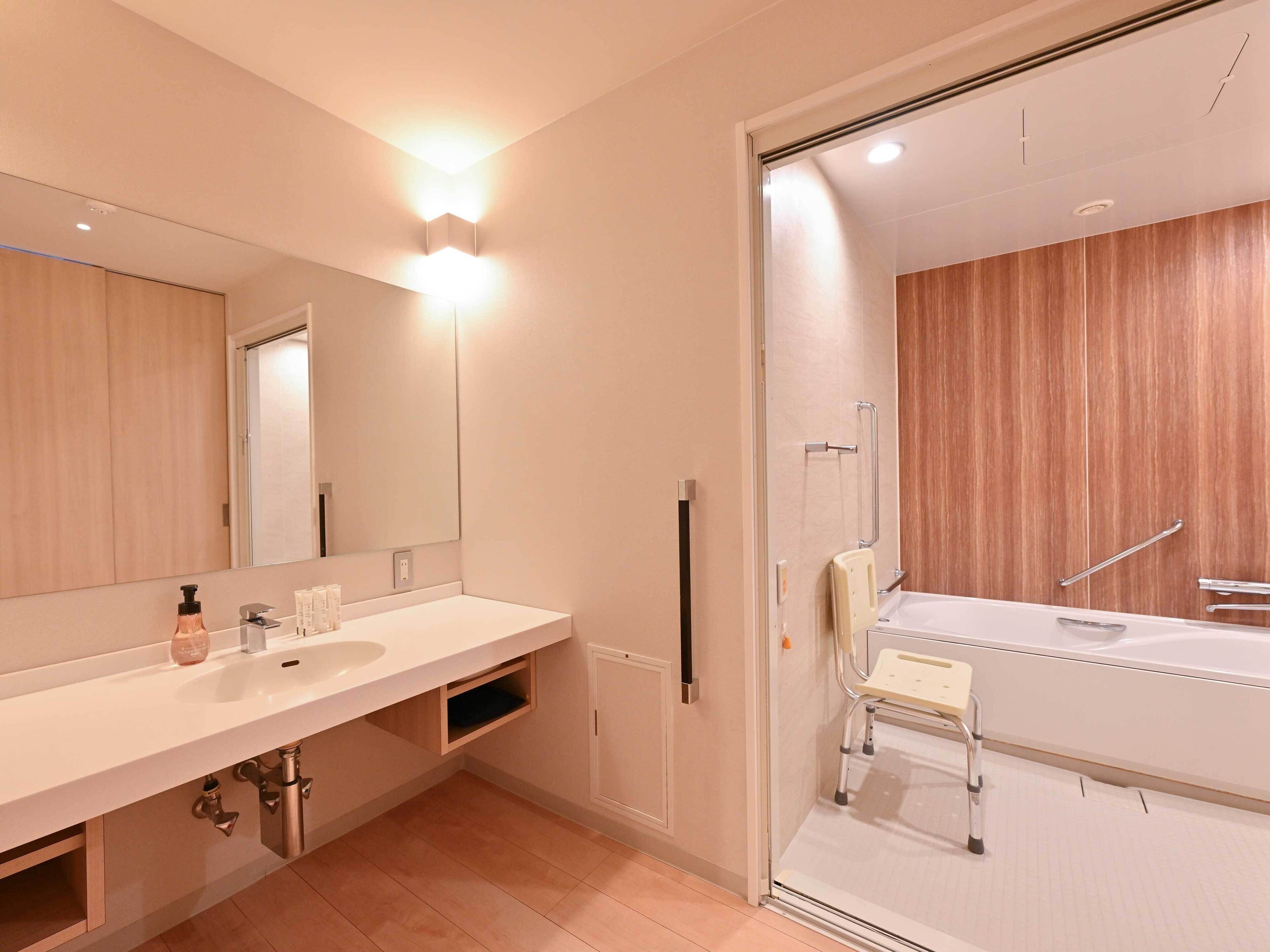 A modern bathroom with a large mirror, two sinks, a shower with a glass door, and a wooden vanity.