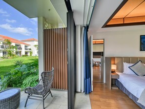 A hotel room with a balcony, a wicker chair, a bed with pillows, and a view of the hotel building and greenery. - Fusaki Beach Resort Hotel & Villas (Ishigaki)