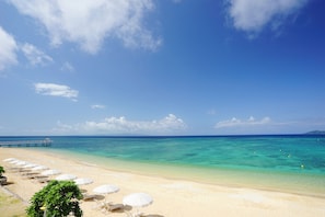 Am Strand, weißer Sandstrand, Sonnenschirme, Strandtücher