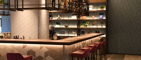 Un bar moderne doté d’un long comptoir, de plusieurs étagères remplies de bouteilles et de tabourets de bar rouges.