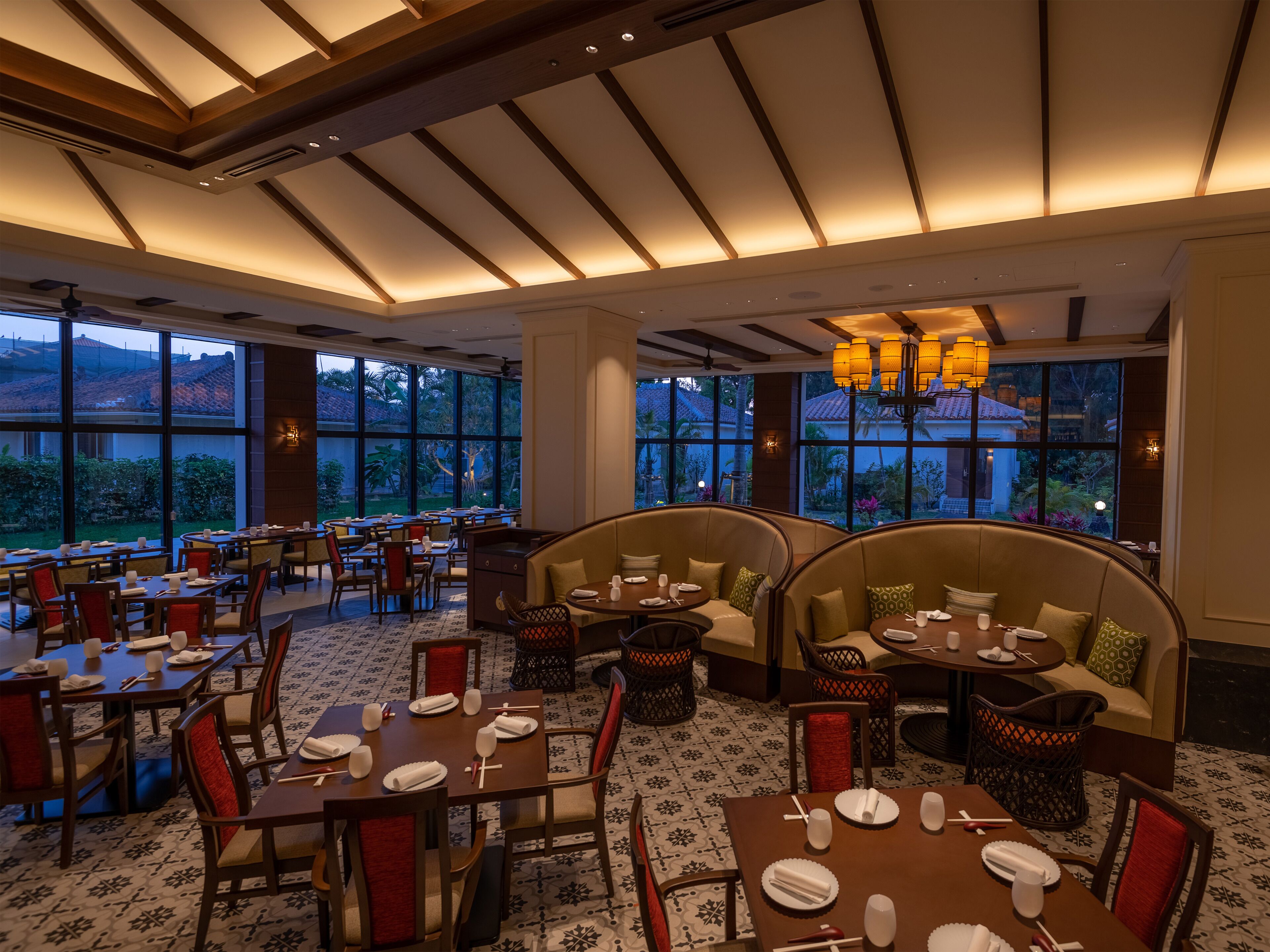 A restaurant with multiple dining areas, including booths and tables, with a view of the outdoors.