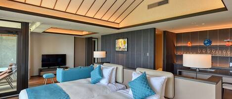 Une chambre d’hôtel moderne dotée d’un grand lit, d’un coin salon, d’une télévision et d’un mini-bar.