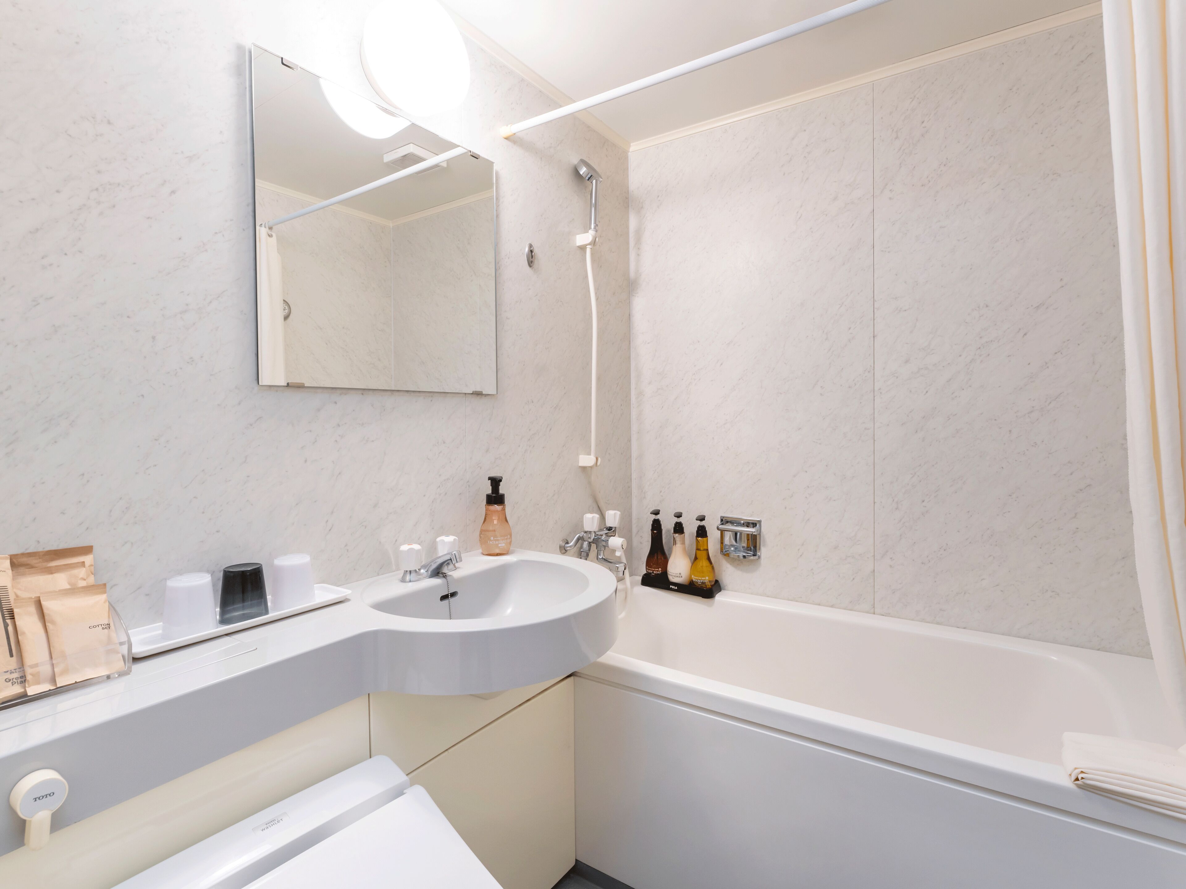 Een moderne badkamer met een witte wastafel, spiegel en douche.