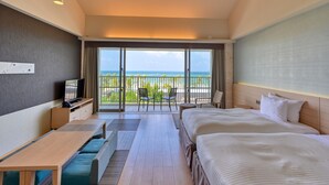 A hotel room with a bed, a desk, a TV, a balcony with a view of the ocean, and a ceiling fan. - Fusaki Beach Resort Hotel & Villas (Ishigaki)