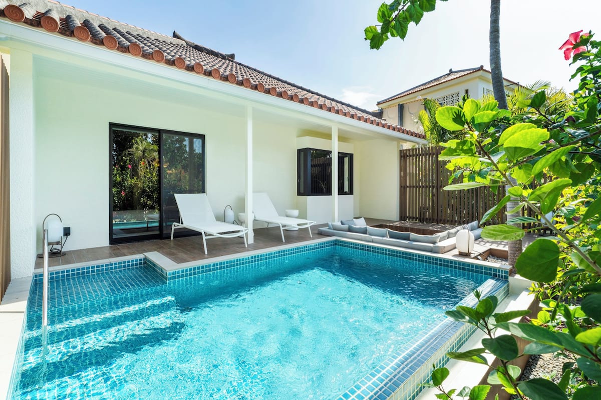A swimming pool with white lounge chairs and a tiled deck.