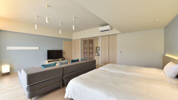 Una habitación de hotel moderna con una cama grande, un sofá, un televisor y un armario.