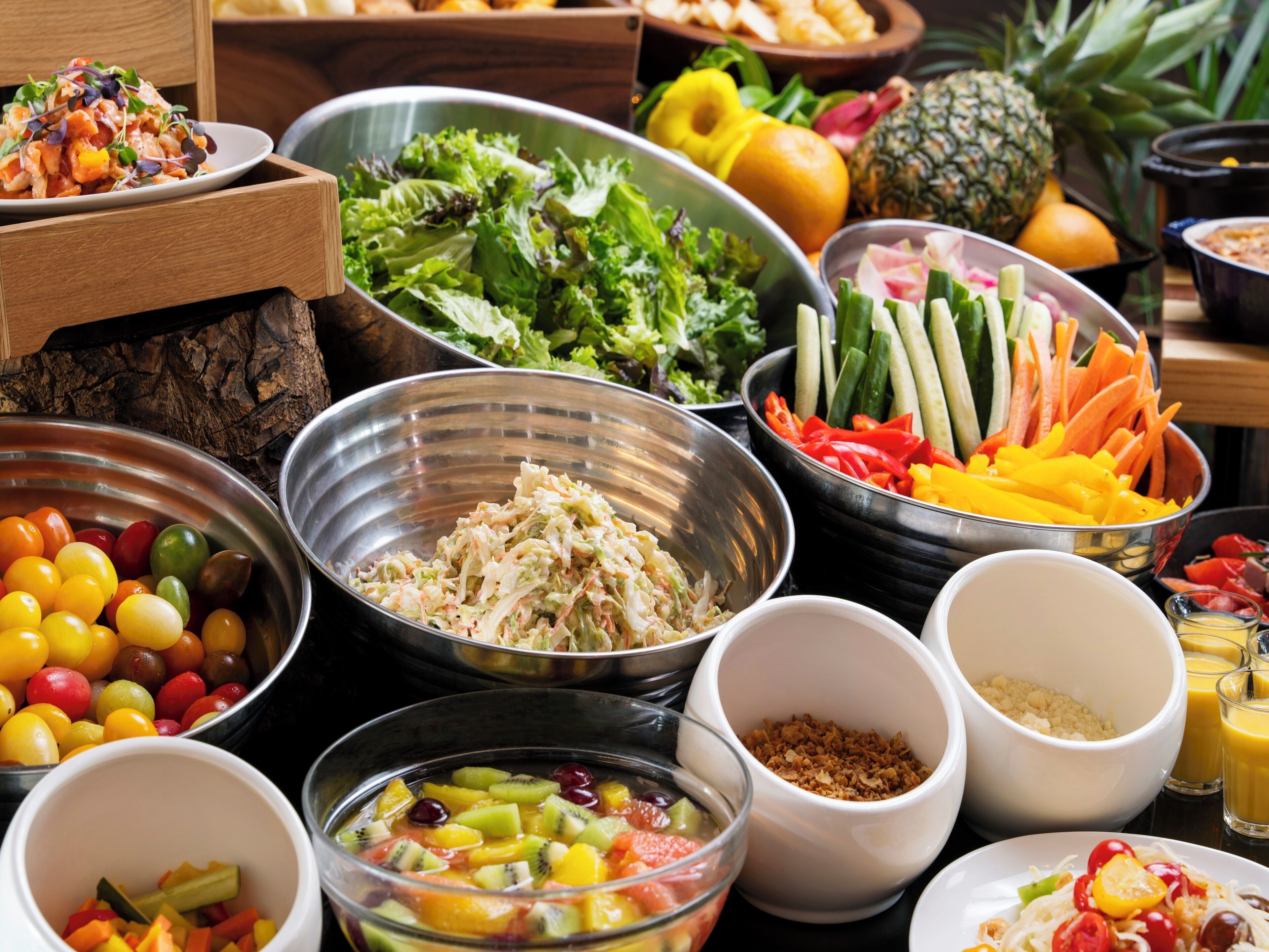 A variety of food items including salads, fruits, and vegetables arranged on a table.