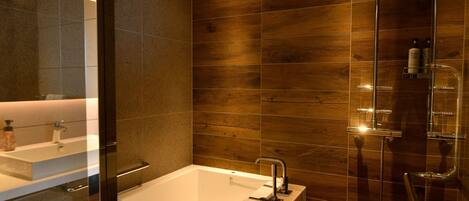 A modern bathroom with a bathtub, a shower, and a large mirror.