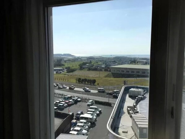 A view from a window overlooking a parking lot with several cars and a building in the distance.