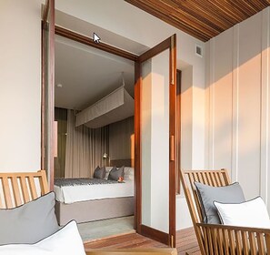 A modern hotel room with a wooden ceiling, a large bed, and a seating area with a view of the room.