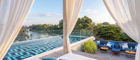 A modern outdoor lounge area with a pool, seating, and a view of a cityscape.